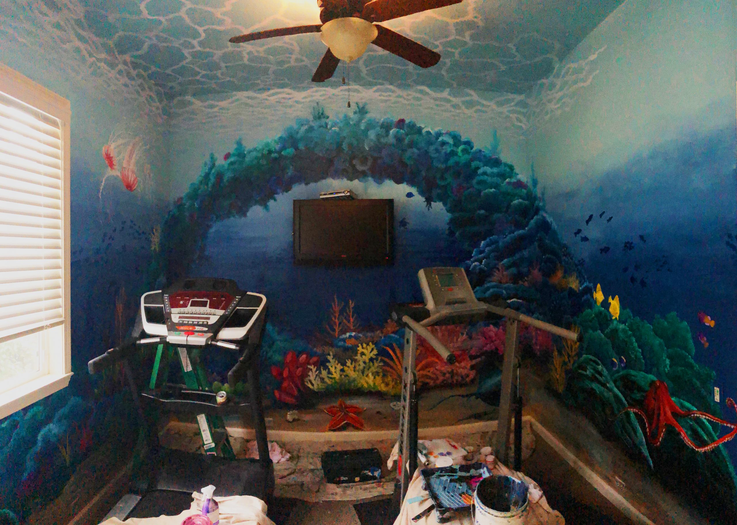 Underwater mural on a home gym wall, full 360 degree with a corral reef and 100’s of fish sea turtles, jelly fish, an eel, and an octopus plus water ripples. Bay Area Muralist.